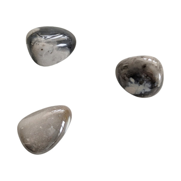 Polished flint tumbled stones with grey, cream, black and brown hues. 