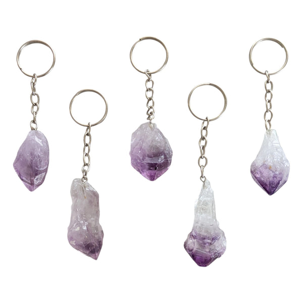Five raw amethyst crystal point keychains with silver-tone metal rings and short chains, arranged on a plain white background.